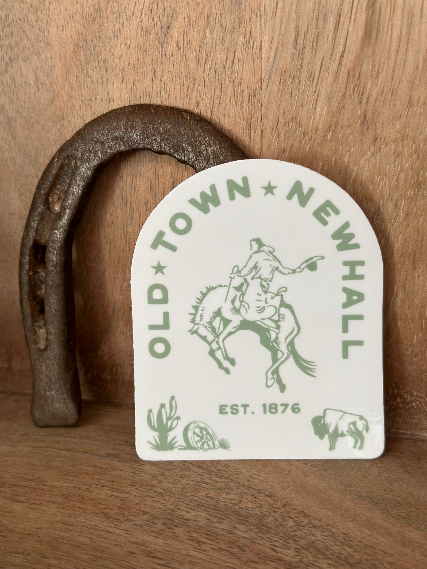 Horseshoe with 'Old Town Newhall' logo on a wooden surface