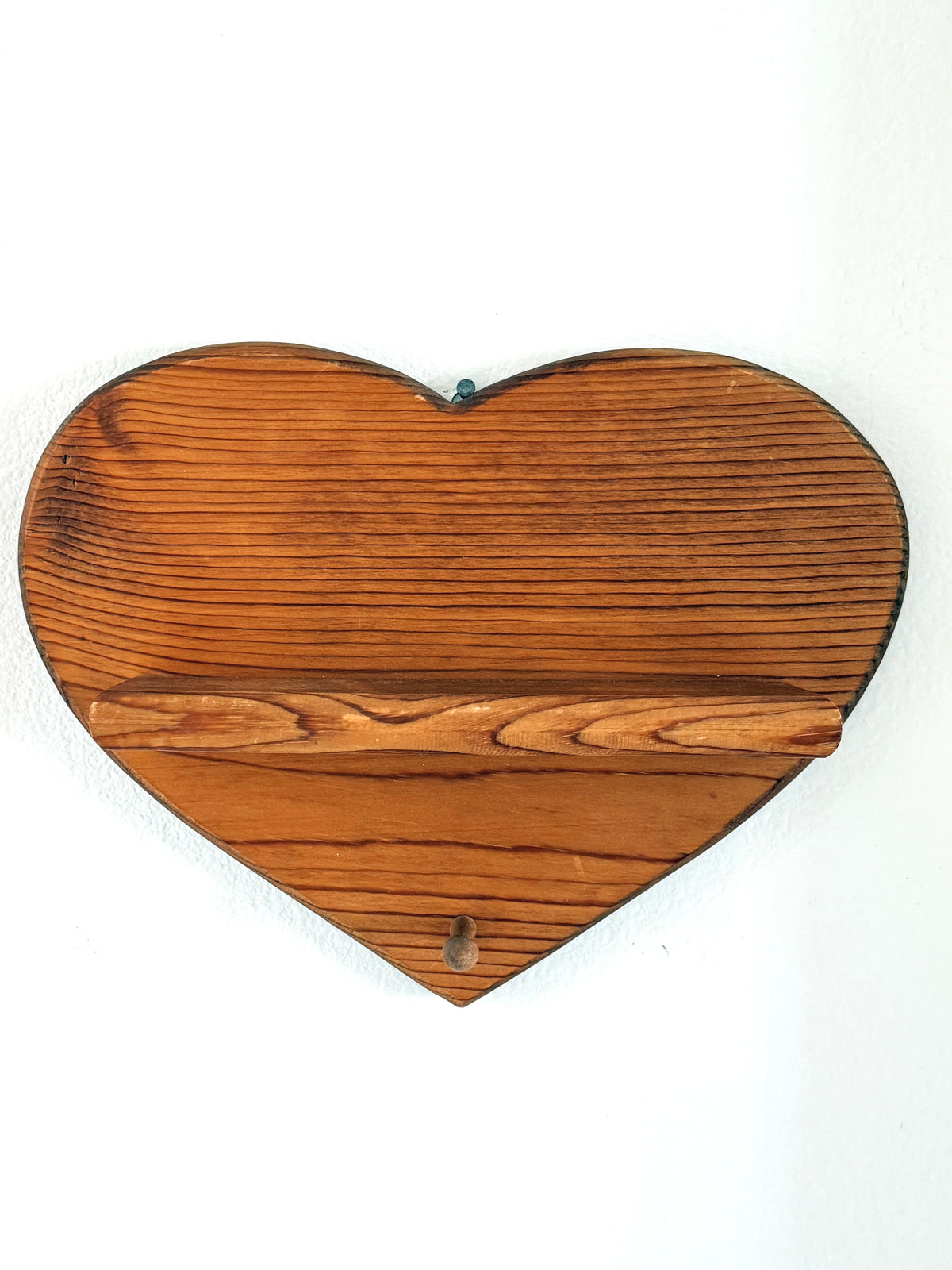 Vintage wooden heart-shaped wall shelf with warm brown wood finish, small display ledge and single hanging peg.