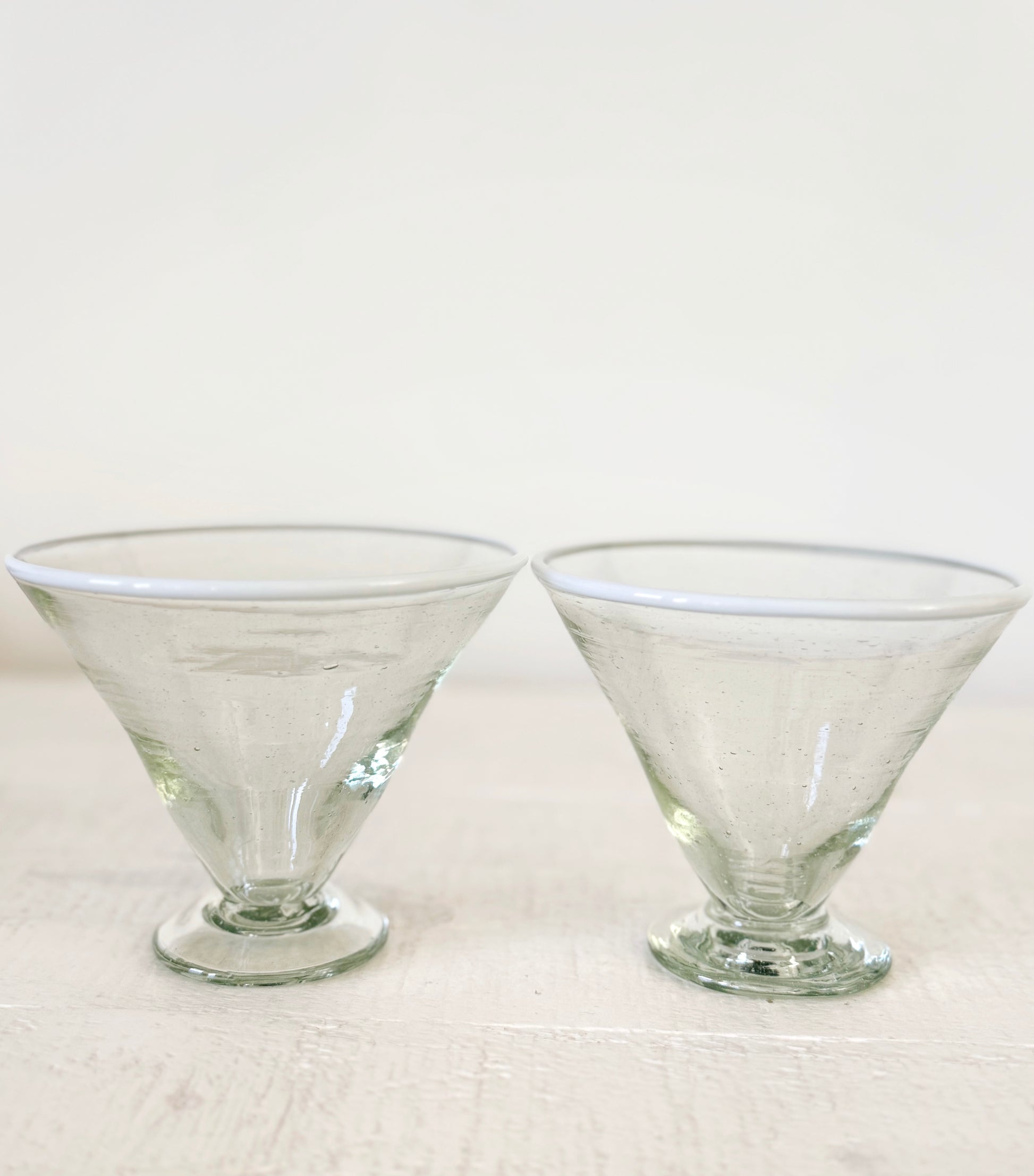 Two clear glass margarita glasses on a white background