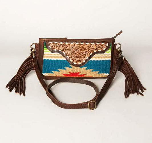 Brown leather handbag with colorful woven top section and tassels on a white background