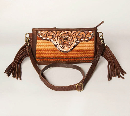 Brown leather handbag with floral tooled design and tassels on a white background