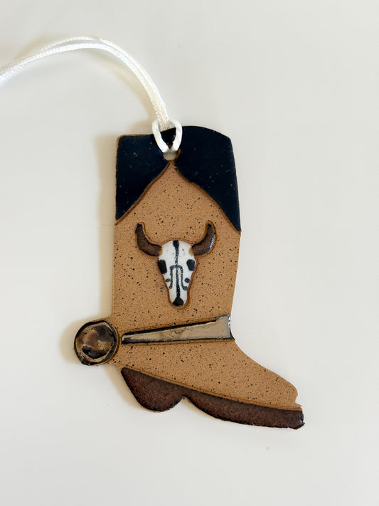 Cowboy boot-shaped ornament with a cow skull design on a white background