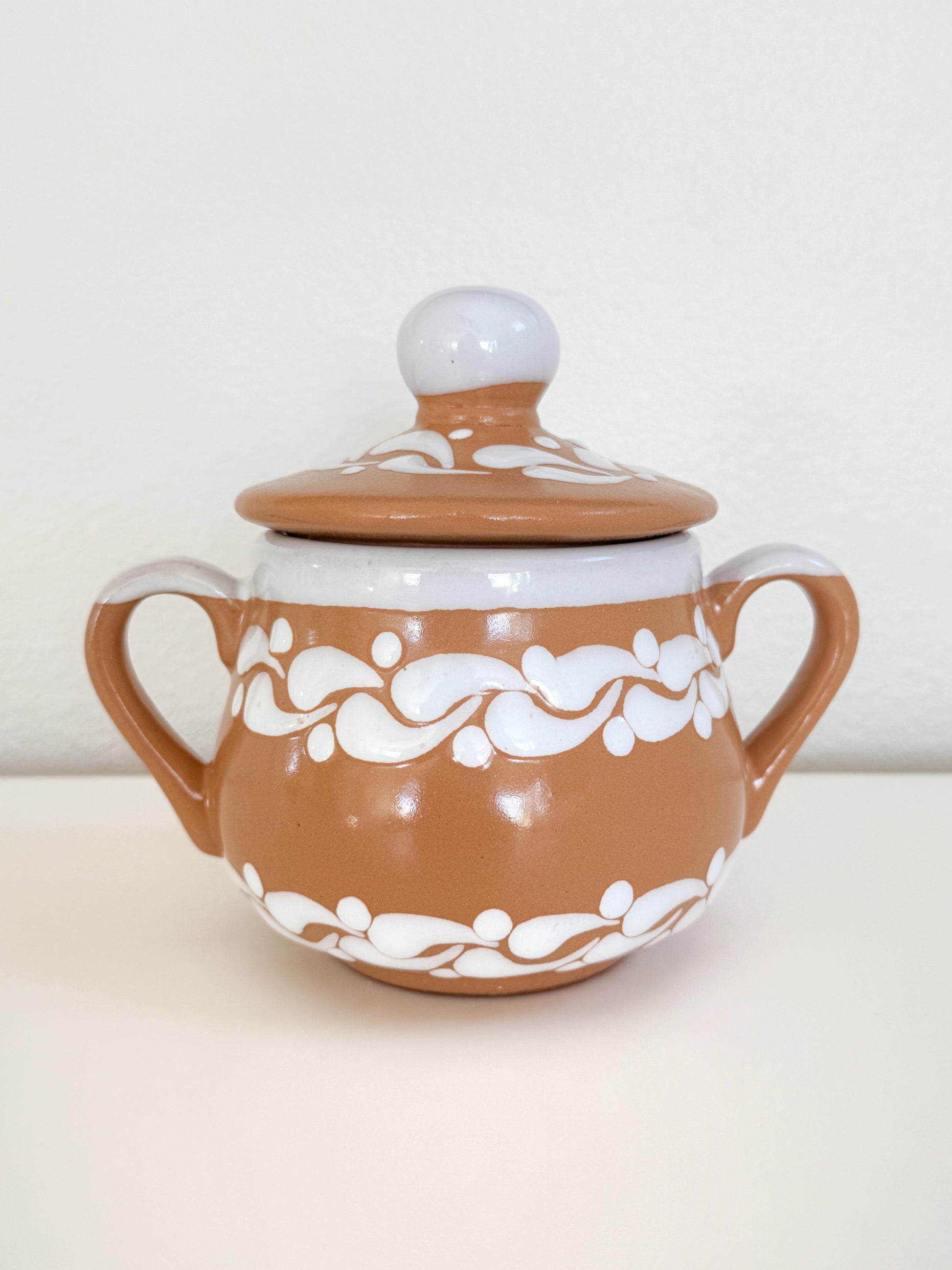 Ceramic sugar bowl with white floral patterns on a beige background
