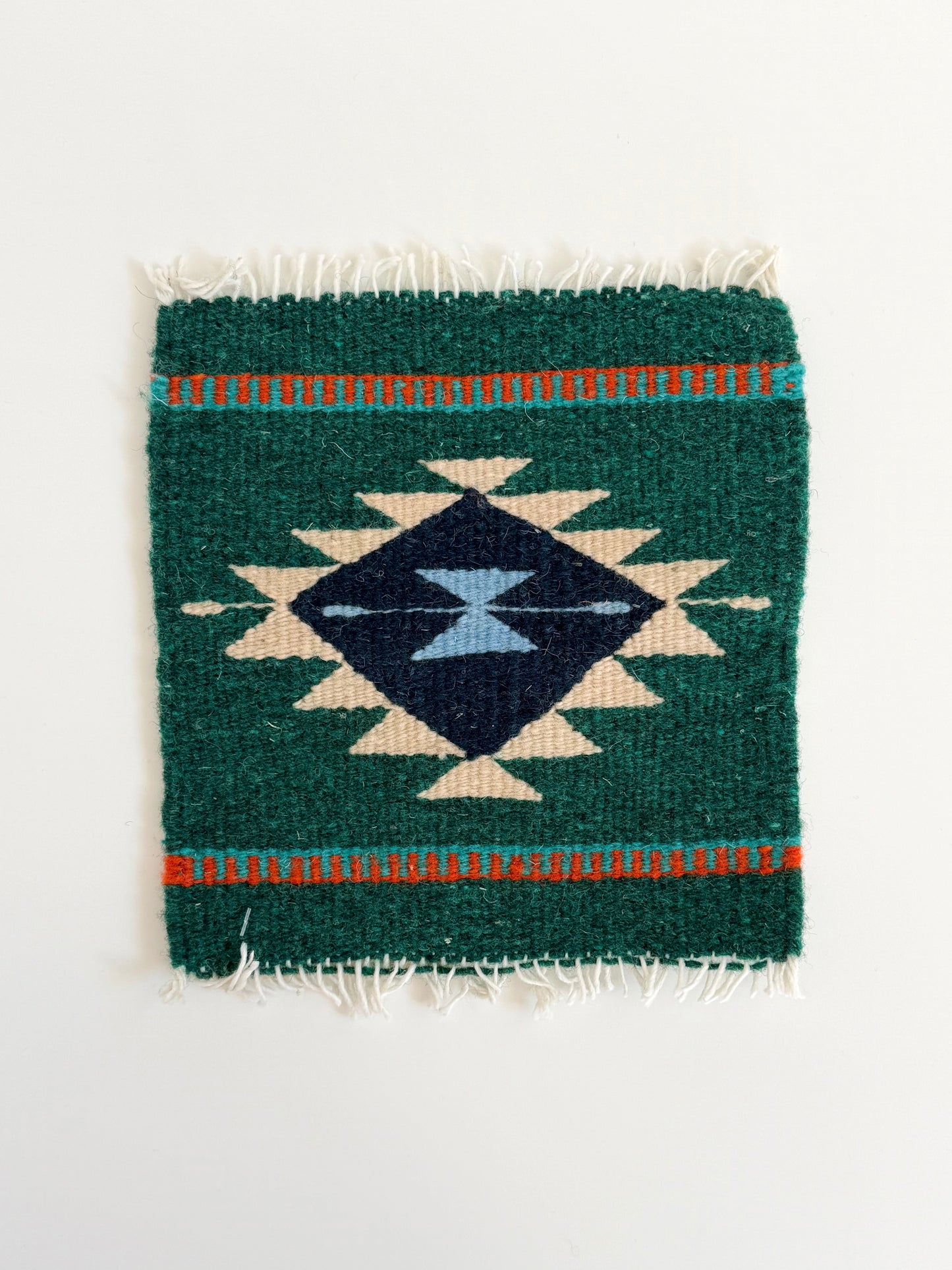 Small woven rug with geometric pattern on a white background