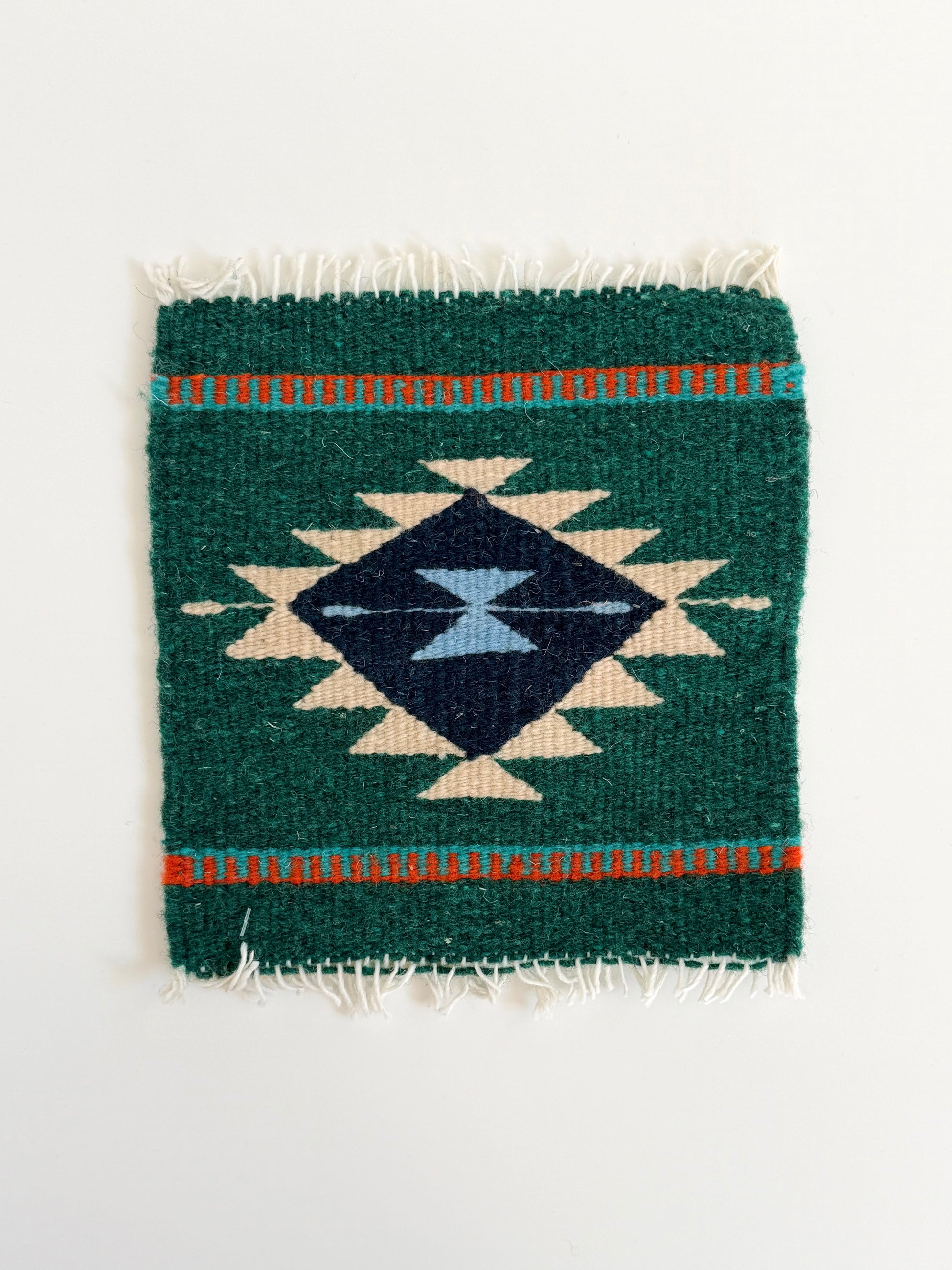 Small woven rug with geometric pattern on a white background
