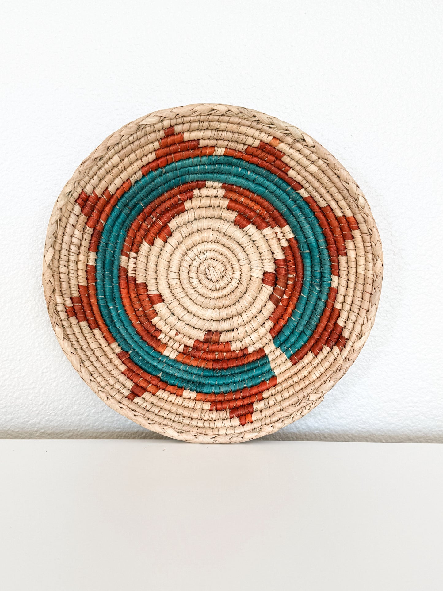 Round woven basket with concentric circle pattern on a white background