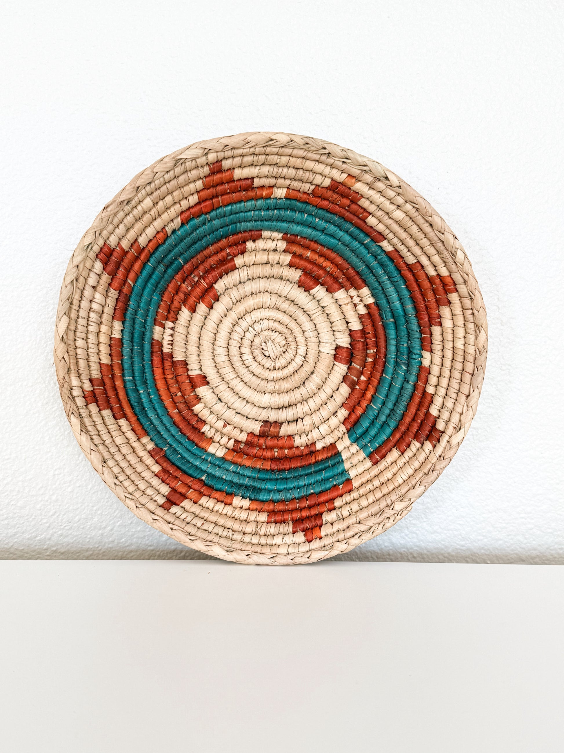 Round woven basket with concentric circle pattern on a white background