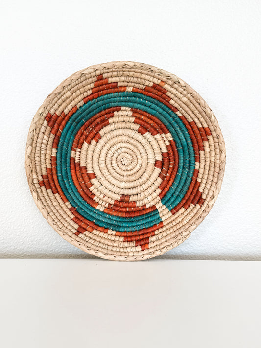 Round woven basket with concentric circle pattern on a white background