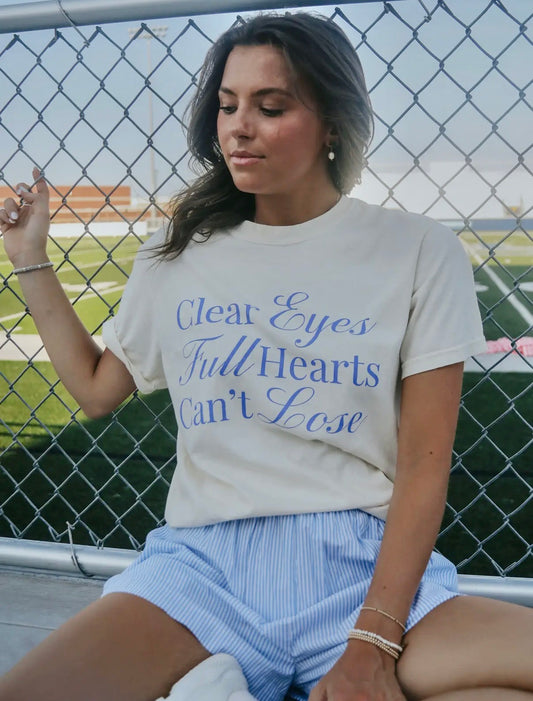 Cream shirt that say “clear eyes full hearts can’t lose” in blue font