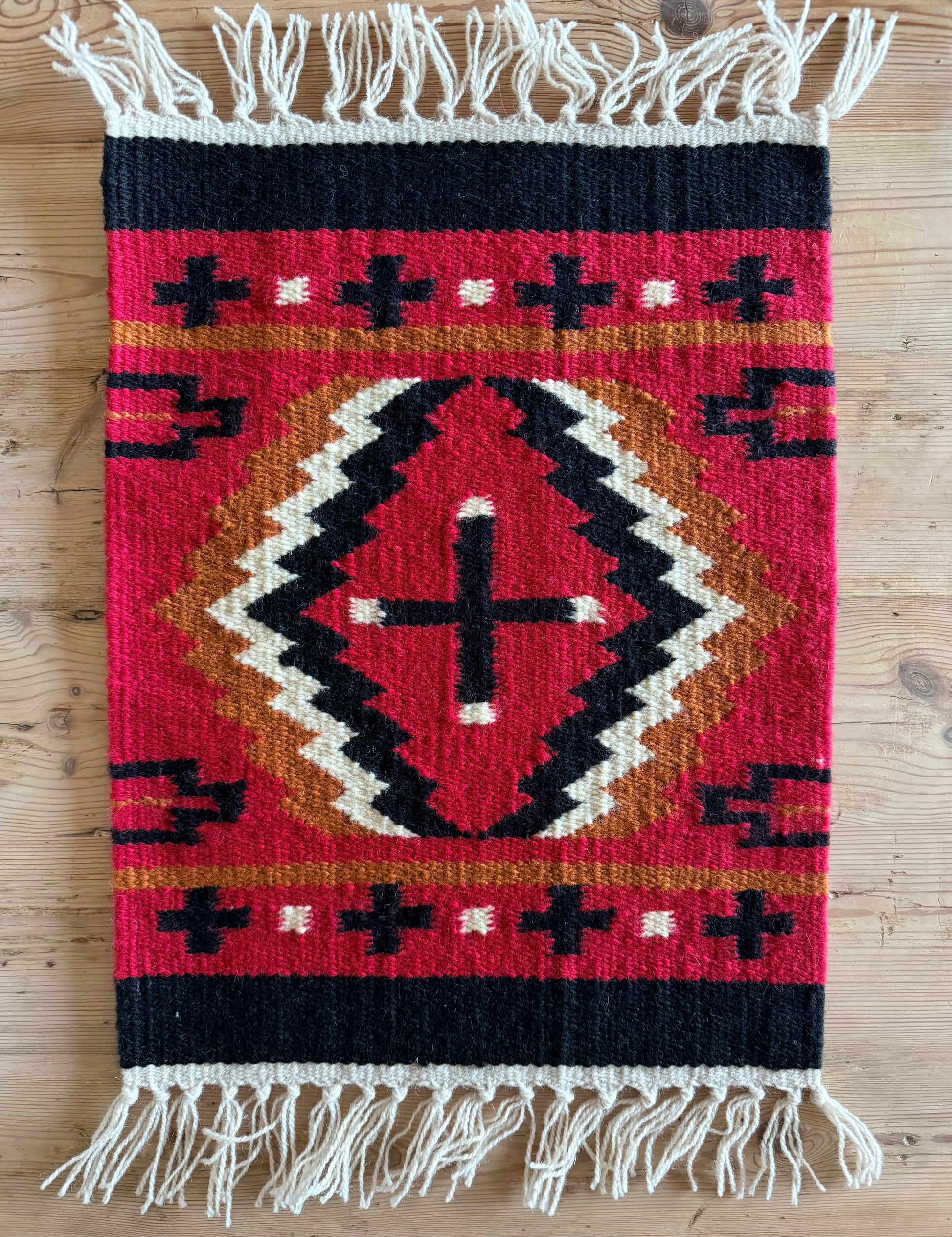 Red and black southwestern wool table mat with geometric pattern
