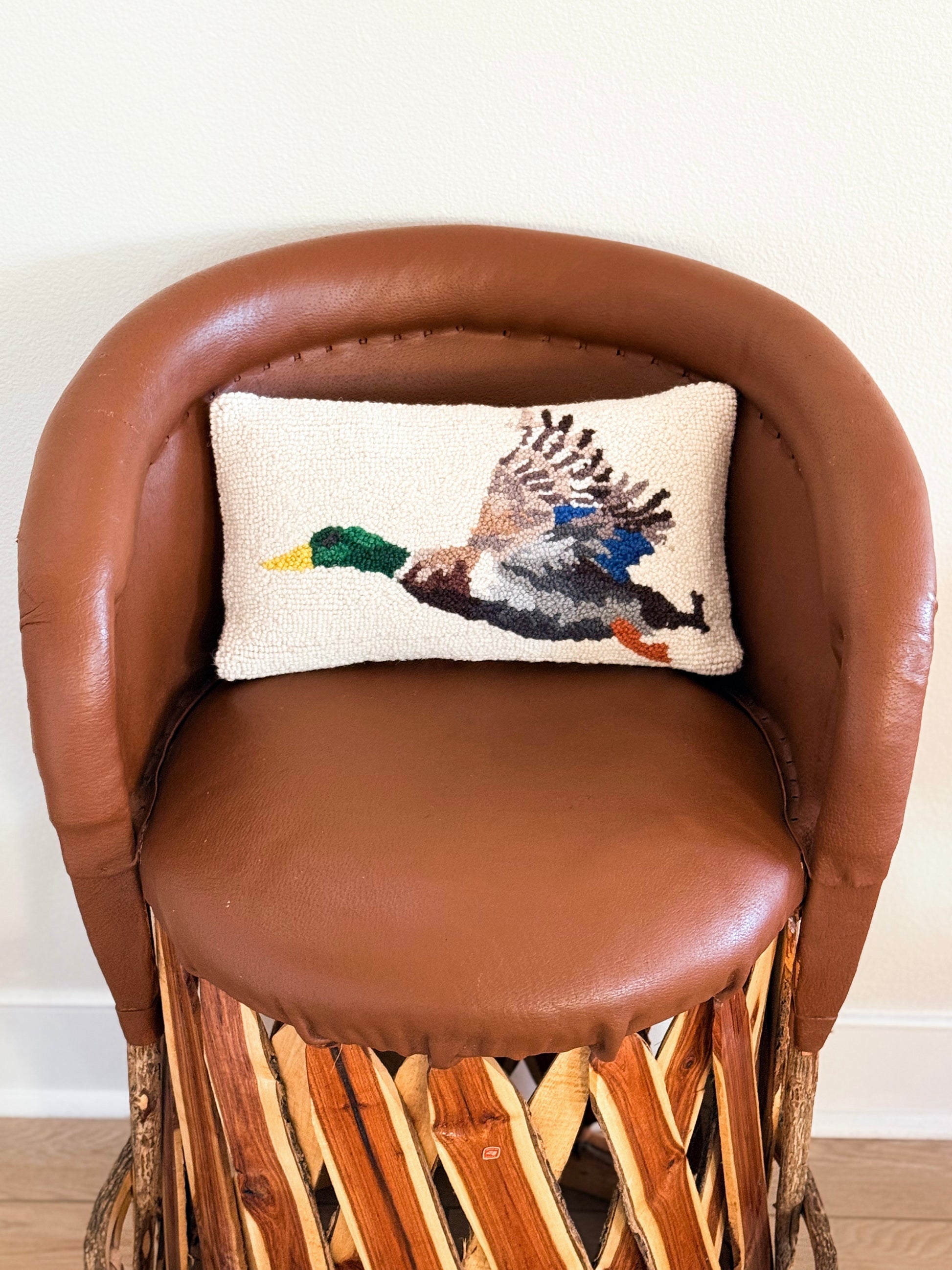 Duck hooked pillow with flying mallard design on southwestern equipale chair