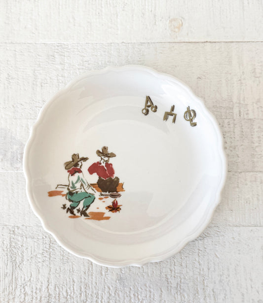 Vintage Syracuse China Sundown bread plate with scalloped edge featuring a western campfire scene and ranch branding symbols.