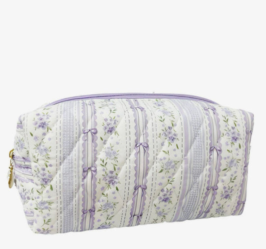 A quilted cosmetic pouch with a lavender and white floral stripe pattern, featuring a top zipper closure and gold-tone hardware, shown against a plain white background.