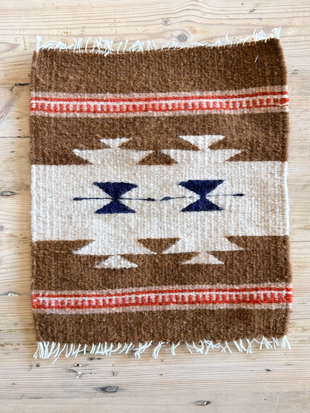 Handwoven wool Southwest table mat with brown, cream, navy and red geometric pattern